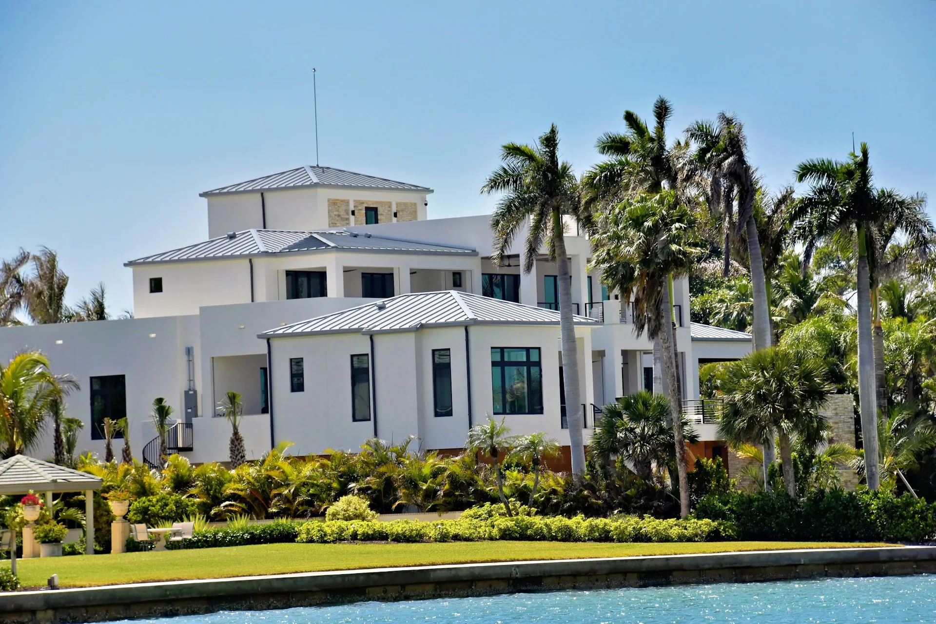 Beautiful white coastal Florida home with palm trees and blue sky